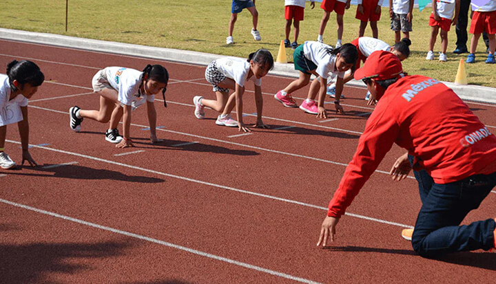 Un grupo de niños en una pista a punto de correr juntos como parte de un evento de «Estrella Colgate».