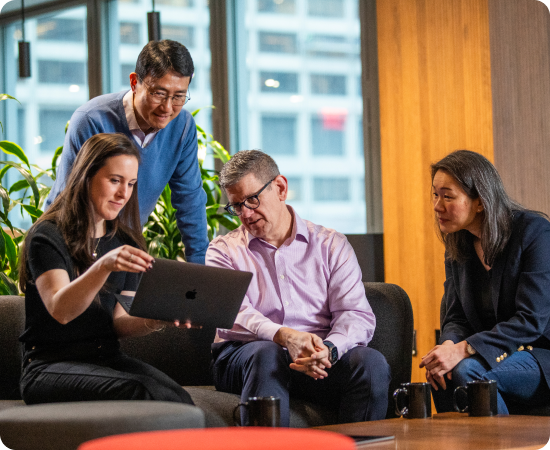 Un grupo de personas mirando una computadora, en representación de la innovación y el crecimiento continuo.
